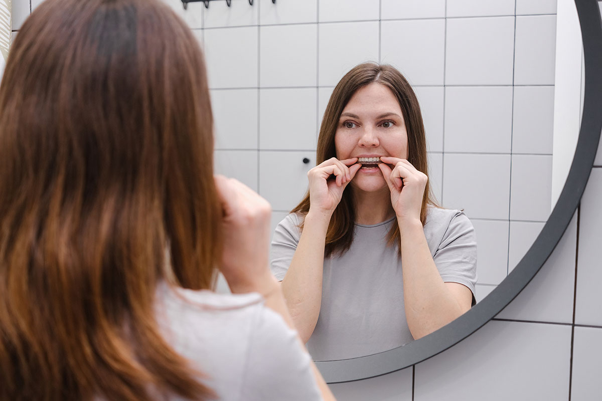 A woman in front of a mirror holding invisalign