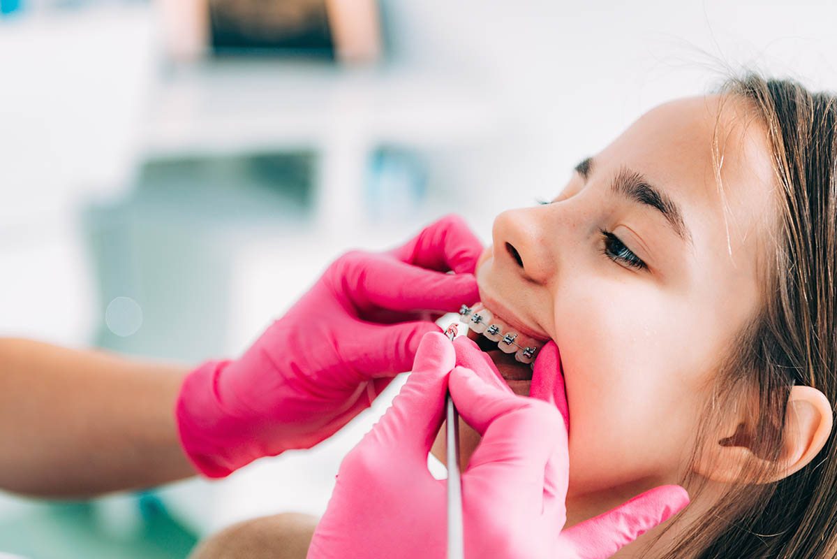 orthodontist checking a girl's dental braces