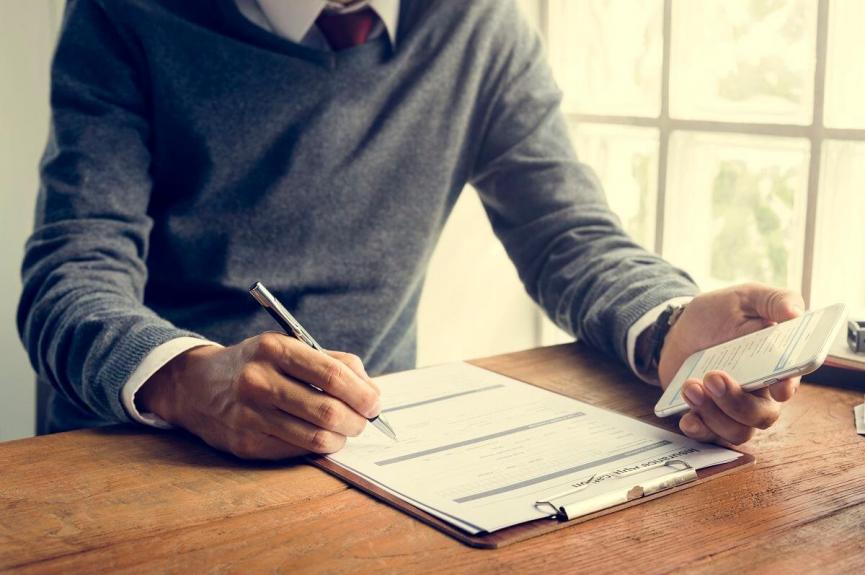 man writing insurance application form