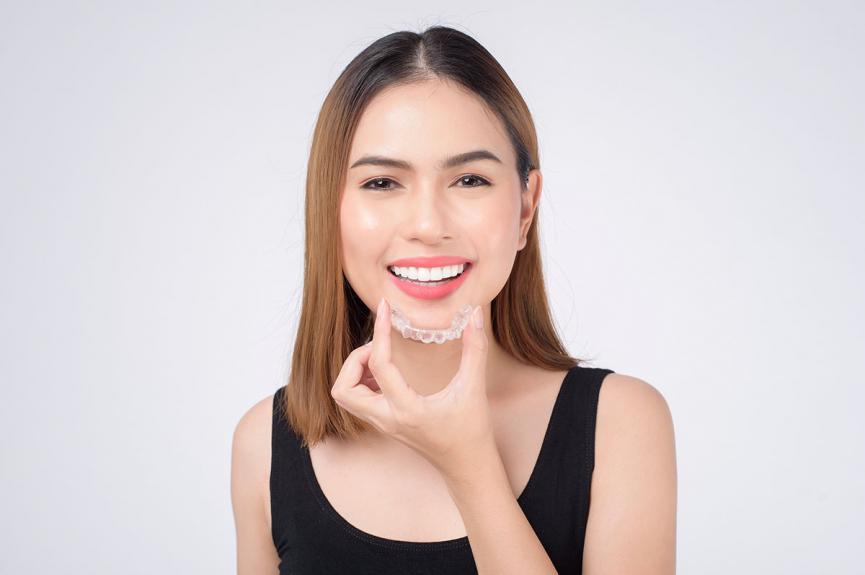 Smiling woman holding invisalign braces Smiling woman holding invisalign braces