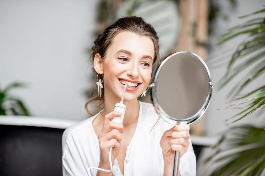 Woman cleaning teeth with irrigator Woman cleaning teeth with irrigator