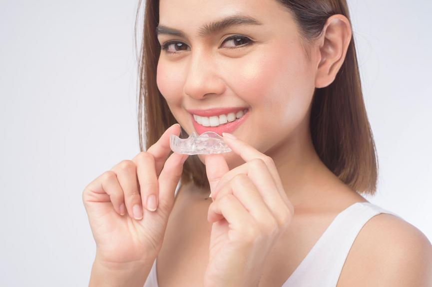Young smiling woman holding invisalign braces Young smiling woman holding invisalign braces