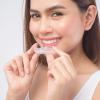 Young smiling woman holding invisalign braces