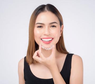 Smiling woman holding invisalign braces