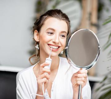 Woman cleaning teeth with irrigator