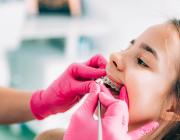 orthodontist checking a girl's dental braces orthodontist checking a girl's dental braces