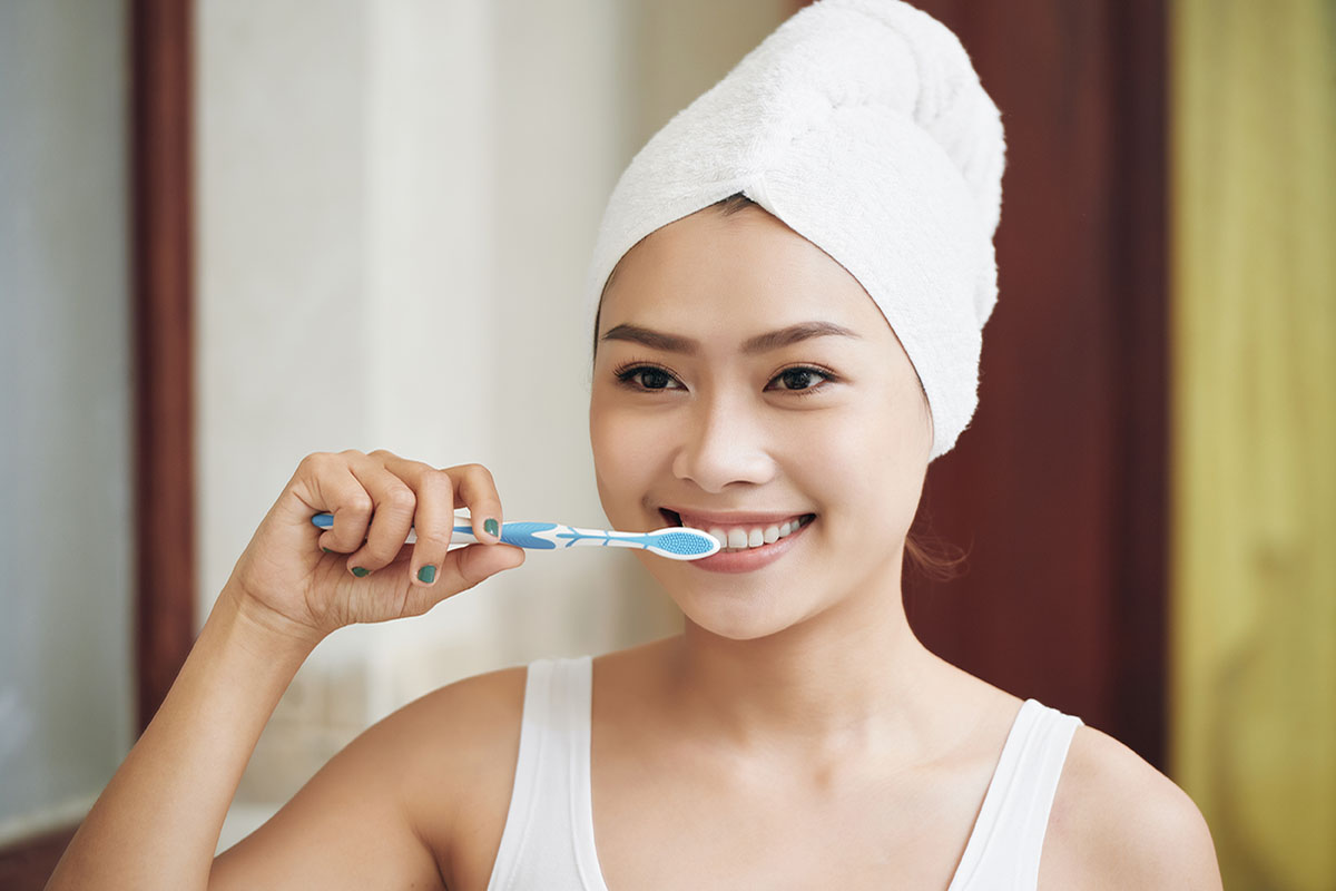 asian woman brushing teeth