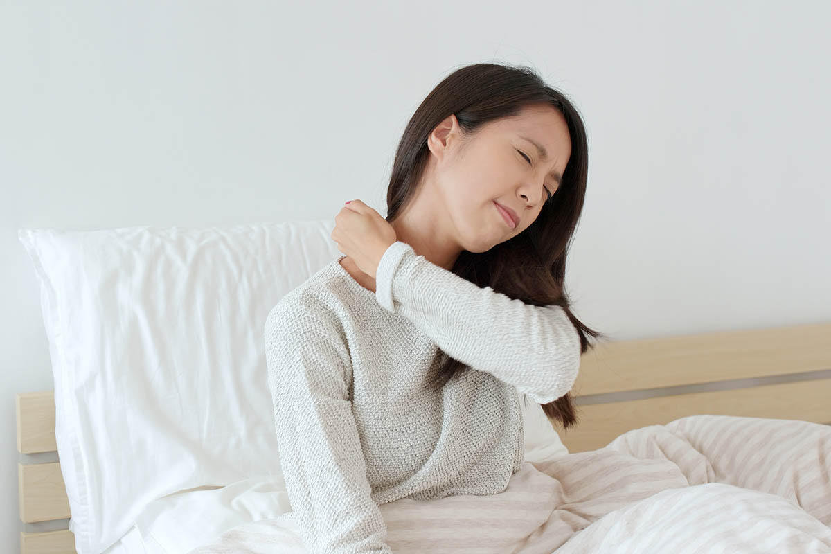 woman rubbing her shoulder to eliviate pain